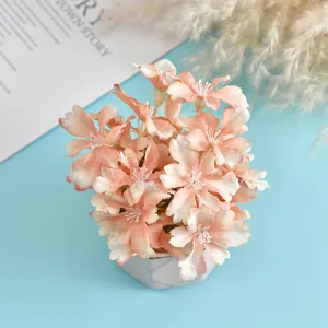 Detailed view of artificial peach pink flower potted plant with modern geometric white vase.