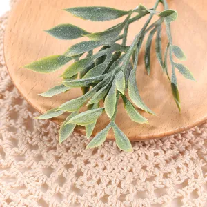 Primer plano detallado de hojas verdes artificiales en plato de madera para decoración.