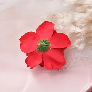 Detailed close-up shot of artificial red flower head, showing soft fabric petals and texture.