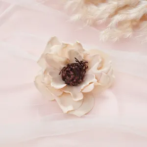 Artificial silk flower detail shot with delicate petals and dark pistil on pink tulle background.