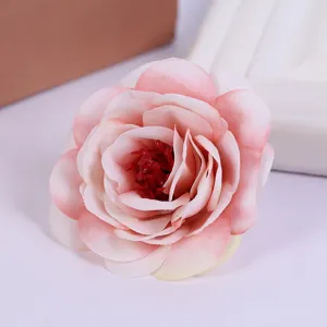 Artificial pink rose flower head detail shot, realistic fabric floral decor for crafts.