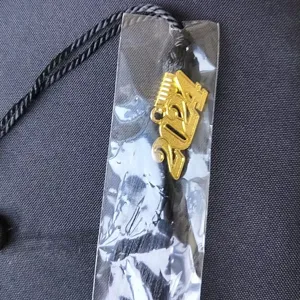 Close-up detail of a black graduation cap tassel featuring a shiny gold 2024 year charm.