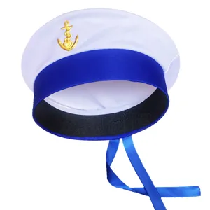 Detalle de sombrero de marinero con ala azul, insignia de ancla dorada y cintas colgantes.