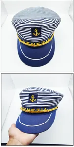 Detailed view of the blue and white striped sailor hat with gold anchor embroidery and rope.
