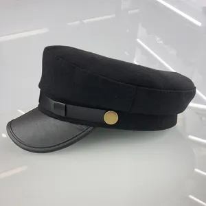 Black wool flat top military hat with leather brim and chic gold button accent for women.