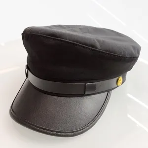 Close-up view of the black sailor hat featuring a leather visor and metal star button.