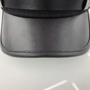 Close-up detail of women's black PU leather naval cap brim showing fine texture.