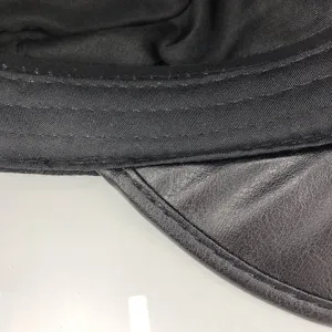 Close-up detail of the black cap's leather visor and fabric inner lining, exquisite stitching.
