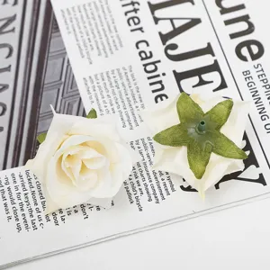 Detailopname van witte kunstrozen bloemhoofdjes met de voorkant en groene kelkbladen.