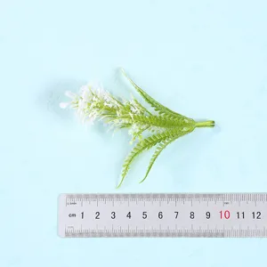 Detailed shot of artificial green plant leaf branch with measuring ruler for scale description.