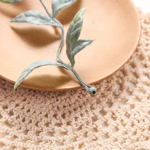 Close-up detail of artificial green plant leaf branch, natural Nordic home decor accessory.