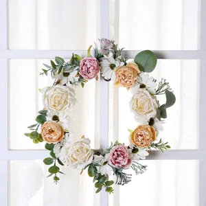 Artificial floral wreath detail, decorative rose and daisy garland hanging on window frame.