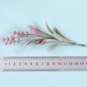 Detail view of artificial decorative plant foliage branch with pink green gradient leaves.