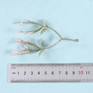 Close-up detail of artificial plant branch with pink buds and green leaves, ideal decor.