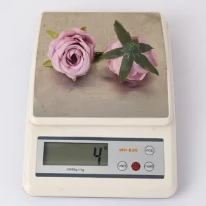 Detailansicht von zwei hellvioletten künstlichen Rosenköpfen aus Seide auf einer Digitalwaage.