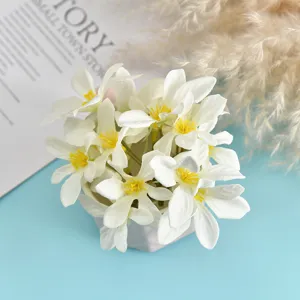 Close-up of white artificial silk flower heads with yellow stamens for DIY props.