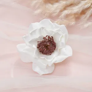 Close up of white artificial peony flower head with detailed dark center and mesh background