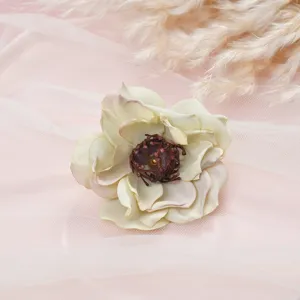 Close-up detail of vintage artificial camellia silk flower with dark stamen on pink tulle.