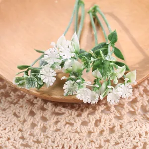 Hojas de plantas artificiales y pequeñas flores blancas para decoración de escenarios.
