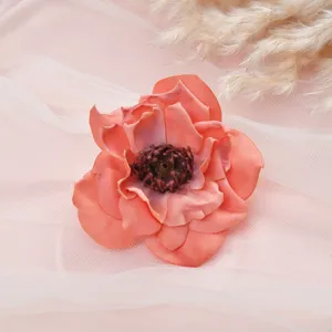 Close-up of vintage pink artificial peony flower, silk material with dark stamen detail.