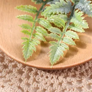 Primer plano detallado de hojas de helecho artificial colocadas en un plato de madera.