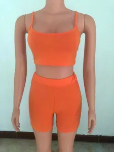 Vista di dettaglio del top corto arancione e pantaloncini con vestibilita slim.