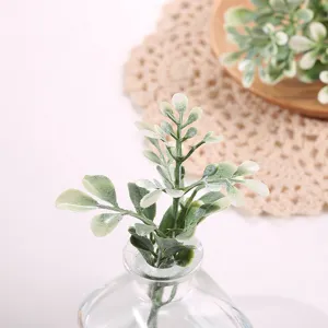 Hojas de plantas verdes artificiales en jarrón de vidrio, ideal para decoración y accesorios.