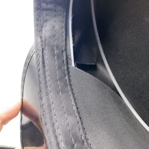 Black patent leather police cap detail shot showing fine stitching and interior lining construction.