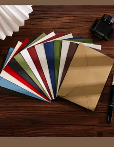 Primo piano di buste di carta colorata disposte a ventaglio su superficie di legno.