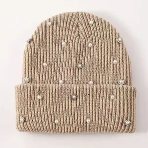 Detail view of winter warm knitted beanie hat embellished with pearls and sparkling rhinestones.