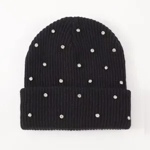 Close up of black knit beanie detail, sparkling rhinestone studded texture, warm winter hat.