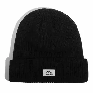 Detailed view of black winter knitted beanie hat with stylish patch, warm and cozy cold cap.
