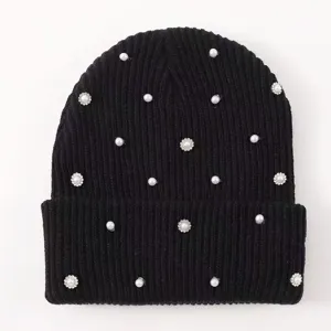 Detail view of a black knitted beanie featuring scattered faux pearls and sparkling rhinestone flowers.