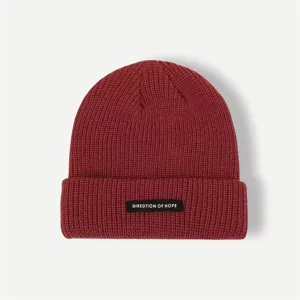 Close-up detail of the dark red knitted beanie showcasing fine ribbed texture and woven label.
