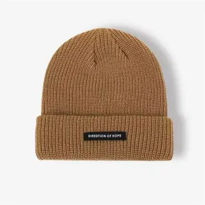Detail view of brown knitted winter beanie hat with black patch, warm and stylish.