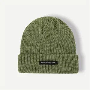 Detail shot of the textured green knit beanie showing the front woven label and fine stitching.
