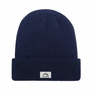 Close-up of dark blue ribbed knit winter beanie hat with white woven logo patch detail.