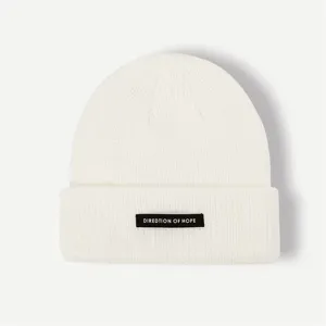 White knit beanie hat with woven label, stylish winter warm casual cap for women men