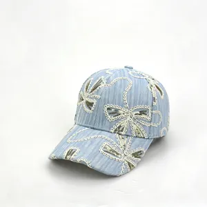 Nahaufnahme der hellblauen Jeans-Baseballkappe mit weißer Spitzenstickerei und Pailletten.