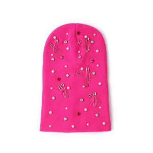 Hot pink knit beanie hat decorated with pearls rhinestones and safety pins detail view