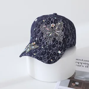 Gros plan d'une casquette de baseball en dentelle bleu foncé avec papillon en strass.