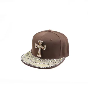 Vue détaillée de la casquette snapback marron avec croix en strass et visière cloutée.