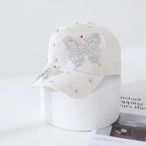 Détail de casquette de baseball en dentelle blanche avec papillon en strass et cristaux.