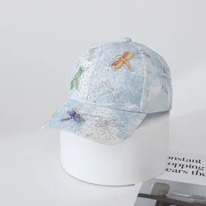 Detailed close-up of light blue tie-dye rhinestone dragonfly fashion cap for outdoor wear.