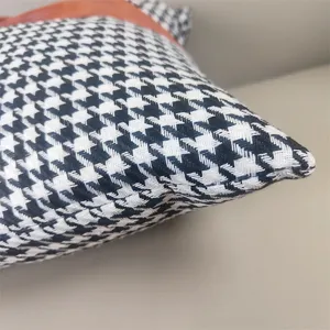Close-up detail of houndstooth and leather splicing sofa cushion fabric texture and edge.