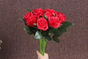Detailed close-up of artificial red soap rose bouquet with green leaves and stems.