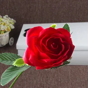 Detailed close-up of a vibrant red artificial soap rose flower with green leaves and stem.
