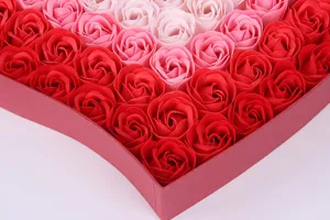 Gros plan d'une boîte-cadeau en forme de cœur remplie de roses en savon dégradées.