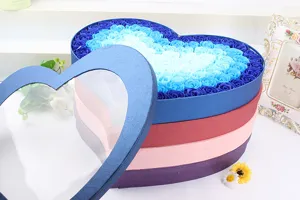Boîte cadeau de fleurs de savon en forme de cœur avec des roses bleues dégradées.