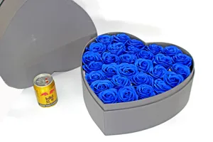 Primo piano di una scatola regalo grigia a forma di cuore con rose artificiali blu.